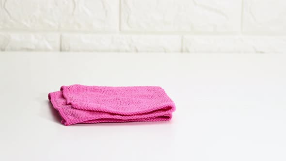 pink cleaning rag and green gloves on white table