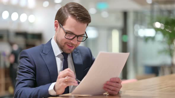 Excited Businessman Celebrating Success on Documents, 