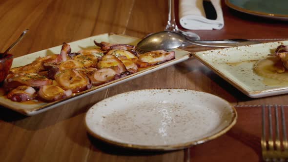 Dolly Tracking Shot of a Restaurant Table with Plates of Grilled Squid and Octopus with Olive Oil