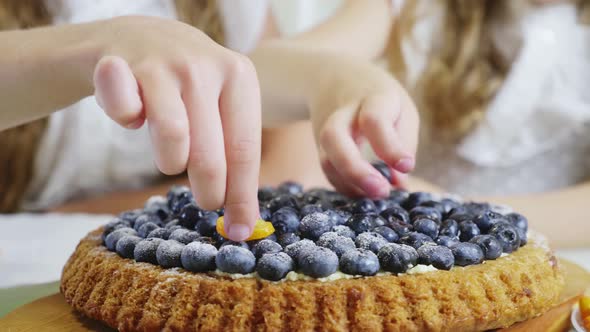 In the Kitchen Concept. The Family Decorates the Pie and Muffins with a Berry