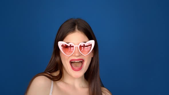 Portrait of a Beautiful Girl in Pink Glasses on a Blue Background