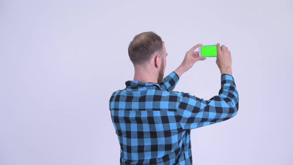 Rear View of Bearded Hipster Man Taking Picture with Phone