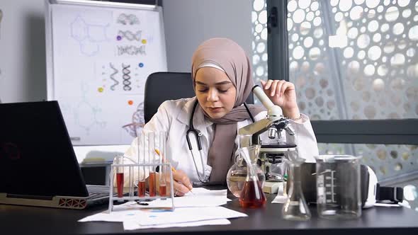 Female Doctor in Hijab which Working with Test Tube with Chemical Liquid in Medical Laboratory