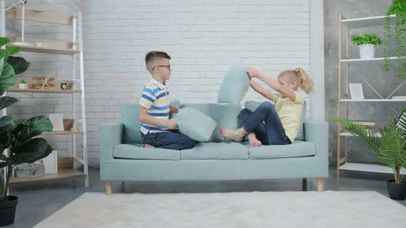 Two Happy Twins Kids Fighting with Pillows at Home