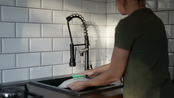 a Woman Washes a Plate in the Kitchen Sink