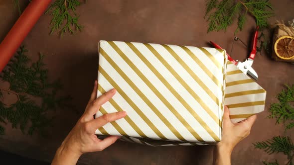 Hands Wrapping Christmas Gift Box with Paper