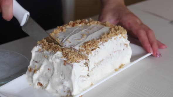 A Woman Cuts A Flaky One Decorated With Biscuit Chips. A Slice Of The Cake Is Visible.