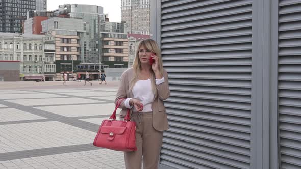 Business woman talking on the phone in the center of a big city.