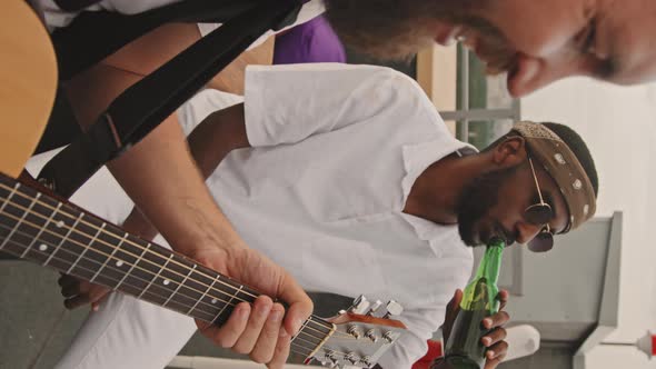 Man Playing Guitar and Friend Enjoying Music at Party