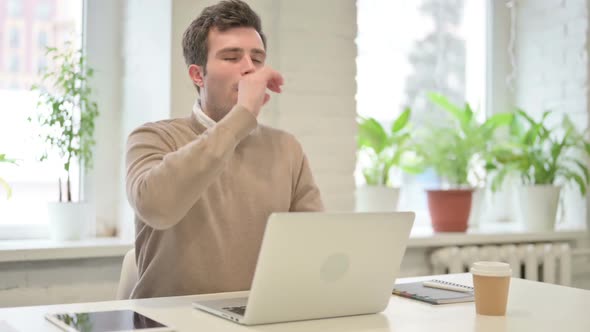 Man Coughing While Using Laptop in Office