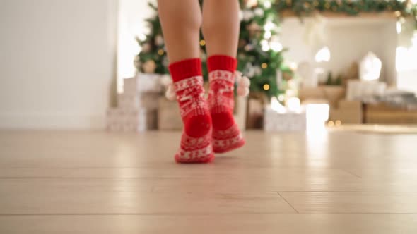 Female Legs in Red New Year's Socks Walking Decorated Christmas Tree with Gifts
