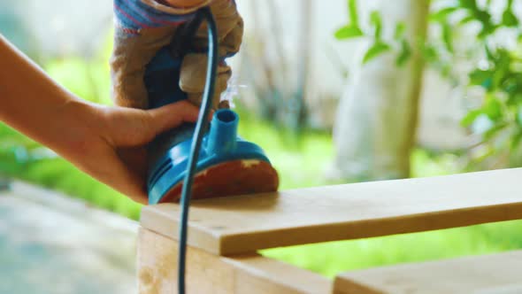 A Young Lady Smoothing Out The Surface Of A Wooden Pallet With A Grinder - Close Up Shot