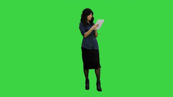 Young Asian Woman Using Digital Tablet and Smiling on a Green Screen, Chroma Key