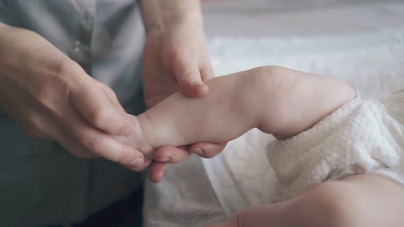 Boy Lies on Changing Table and Nurse Performs Legs Massage