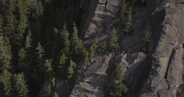 Aerial Drone Shot Flying Up Past Jagged Rocky Cliffs On Mountain