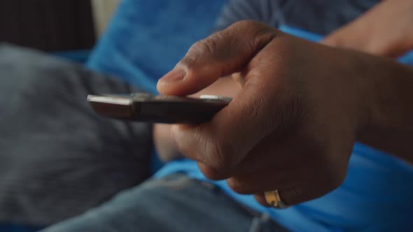 Closeup of Black Male Hand Changing Tv Channels with Remote Control