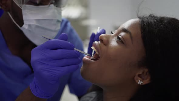 Closeup of Pretty African Young Woman Patient Being Examined By Male African American Doctor Dentist