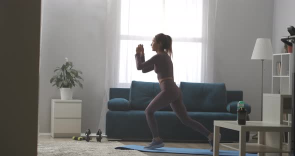 Athletic Woman Is Squatting and Jumping in Living Room of Modern Apartment Home Fitness Training