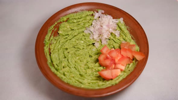 Extreme closeup top view of avocado smash rotating. Traditional tasty sauce guacamole. Adding papper