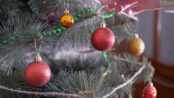 Female Hands Decorate Christmas Tree with New Year Christmas Decorations