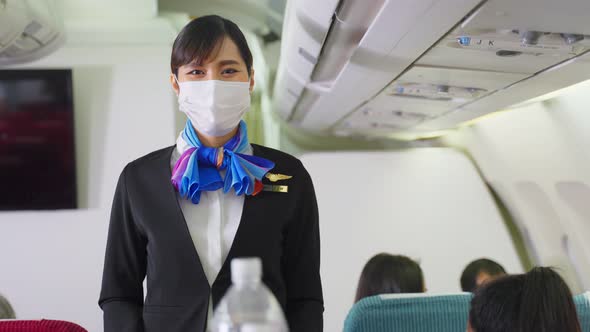 Cabin crew wear mask, pushing service cart and serve to customer on the airplane during flight.