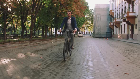 Handsome Young Man Driving His Bicycle on the Street in Park in City Center During Sunrise Slow