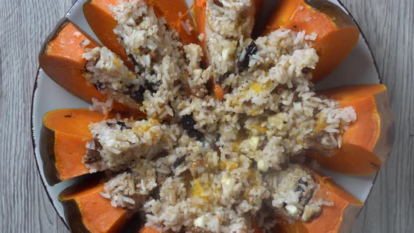 Stuffed roasted pumpkin, baked with a filling close-up on a plate, rotates