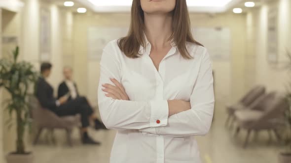 Unrecognizable Businesswoman Crossing Hands and Smiling in Business Center. Portrait of Confident