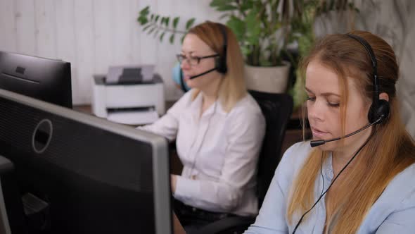 Two Female Call Center Operators with Headset Work in a Support Service Office