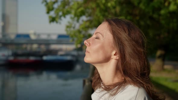 Closeup of a Brunette's Face on the City Embankment on a Sunny Day