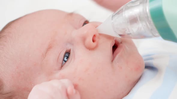 Closeup of Using Nasal Aspirator for Cleaning Newborn Baby Nose From Mucus