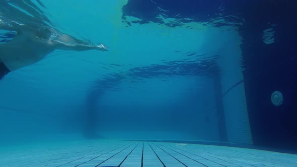 A Man Swims on the Surface of the Water in the Pool From Left To Right. Shooting From Under Water. 