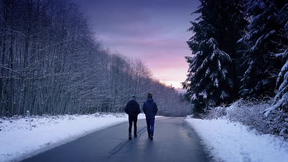 People Walking Through Snowy Woods At Sunset