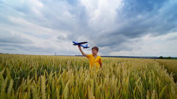 Cute boy with a toy plane. Little kid playing among agriculture field under clouded sky. Summer vaca