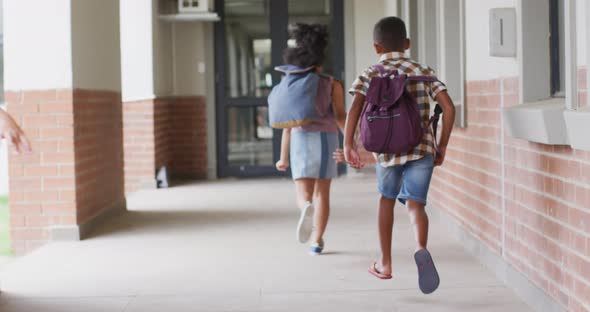 Video of back of diverse pupils running on school corridor