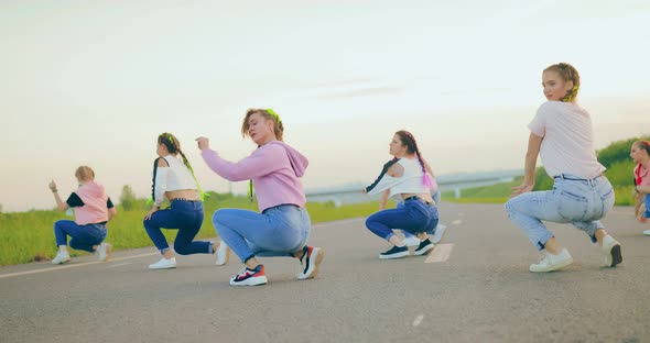 Group of Young Women Dancing Synchronously on the Road
