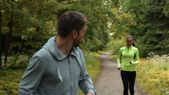 Young Runner Guy Run with Woman Falls Behind in Park