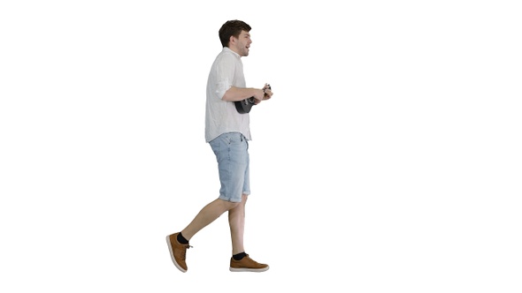 Young man playing a ukulele singing and walking on white