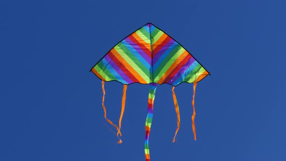 Aerial Multi-colored Kite Flies Against the Blue Sky. Games and Entertainment in Nature