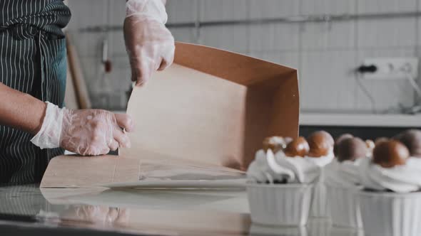 A Chef Collects a Cardboard Box to Send Out Decorated Cupcakes