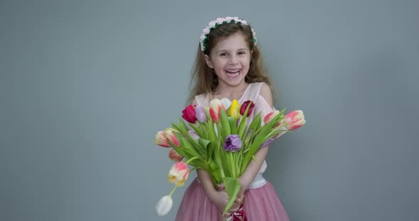 Cute Small Kid Child Holding Tulips and Smiling to the Camera