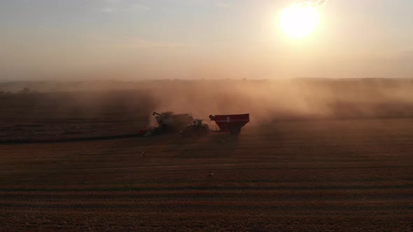 Aerial shot: combine pouring harvested wheat into tractor tipper