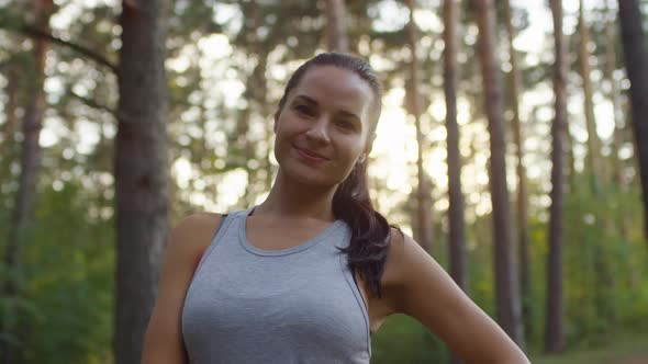 Pretty Brunette Sportswoman Smiling at Camera in Forest