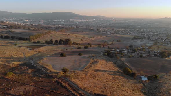 Expansive aerial pan down of the countryside in Colima, Mexico at sunset.