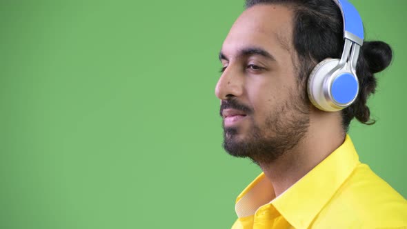 Profile View of Young Handsome Bearded Indian Businessman Listening To Music