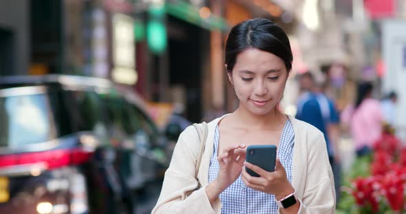 Woman checking on cellphone in the street