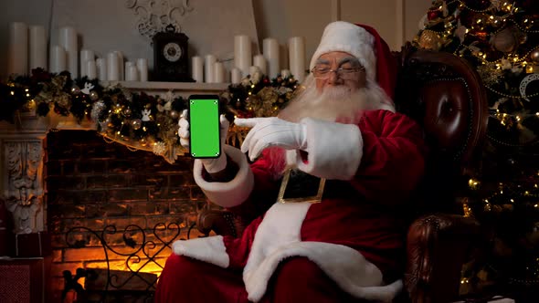 Modern Smiling Santa Claus Points Finger at Smartphone Green Screen Markers