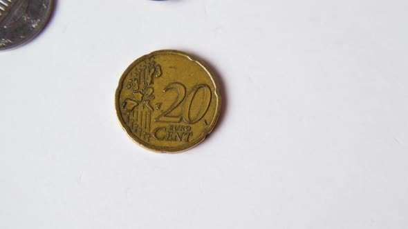 A yellow coin with a face value of 20 euro cents falls on a white background. Close-up