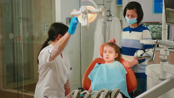 Pediatric Dentist and Assistant Treating Girl Patient in Stomatological Clinic