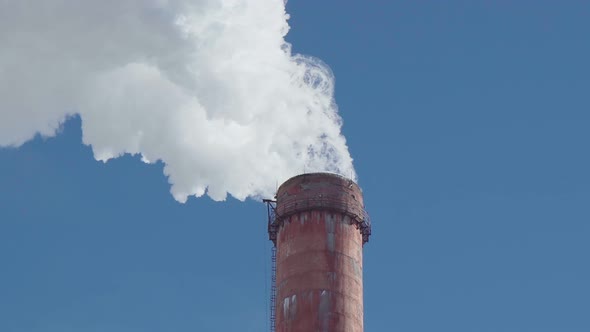 Smoke Emissions From Industrial Chimney Against Blue Sky Background